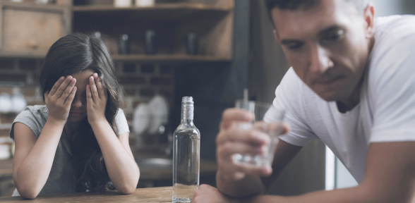 Fetița plânge, acoperindu-și fața, tatăl alcoolic se întoarce rușinat